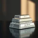 Stack of silver bullion bars on a dark surface with soft lighting.