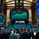 NYSE trading floor with green monitors showing S&P 500 index reaching record highs during AI-driven market rally.