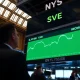 New York Stock Exchange trading floor with green screens showing S&P 500 record high