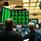 Traders on the NYSE floor watching green stock ticker during market rally