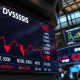 Stock market board showing red declines and a crude oil price ticker surging upward on a trading floor.