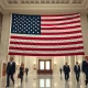 American flag inside a federal government building hallway with officials walking