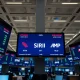 Stock exchange floor with digital screens showing options data for Rivian, SiriusXM, and MP Materials