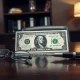 US dollar banknote on desk with reading glasses and pen, representing forex and Fed policy analysis.