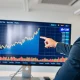 Financial analyst pointing to a digital screen showing a Bitcoin price chart with an upward trend and a $1M indicator