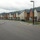 Row of new homes in a UK housing development with 'For Sale' signs under overcast sky