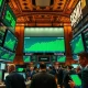 Stock exchange trading floor with green screens showing S&P 500 and Nasdaq at record highs