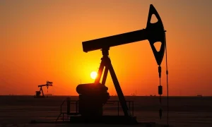 Oil pumpjack silhouette against sunset sky with faint US and Iran flags