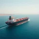 Oil tanker sailing through the Strait of Hormuz under clear daylight, representing global crude supply routes.