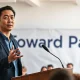 Andrew Yang speaking at a Forward Party community event, gesturing while addressing an audience.