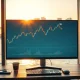Forex trading monitor showing AUD/USD candlestick chart in Sydney office with harbour view