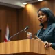 Kemi Badenoch speaking at a podium in a City of London conference hall