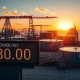Brent crude oil price ticker showing $80 at sunset with storage tanks in background