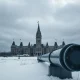 Canadian Parliament buildings on a grey winter day with a pipeline in the foreground