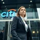 A woman in a business suit exits a Citigroup office building in a financial district.