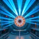 Interior of a laser fusion reactor hall with laser beams converging on a fuel target chamber