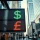 Currency exchange board showing US Dollar and British Pound rates in a financial district