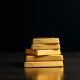 Stack of gold bullion bars on a dark surface with soft lighting