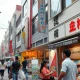 Shoppers on a Tokyo street with visible price signs, representing Japanese consumer inflation.