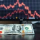 Japanese Yen and US Dollar banknotes on a desk with a financial chart in the background.
