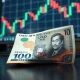 Japanese yen banknote on desk with USD/JPY chart on monitor in background