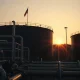 Oil storage tanks at sunset reflecting geopolitical tension and rising crude prices