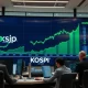 A stock market display board in Seoul showing green charts, reflecting the KOSPI's rally on AI optimism.