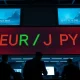 Trading floor with digital display showing EUR/JPY exchange rate data.