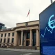 European Central Bank building in Frankfurt with a digital euro symbol and downward chart trend.