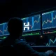 Trading monitors showing cryptocurrency charts with an upward trend, representing Hyperliquid's HYPE token price movement.
