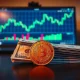 Mexican peso coin and US dollar bills on a desk with a trading chart on a monitor in the background