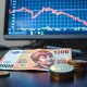 Indonesian rupiah banknotes and coins with forex chart showing downward trend