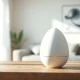 A minimalist white smart speaker device on a table in a sunlit modern room, representing OpenAI's new hardware.