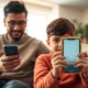 Parent and child sitting together on a sofa, both holding smartphones, representing kid-safe phone options.