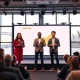 Entrepreneurs pitching on stage at a startup competition in Sydney with Harbour Bridge visible