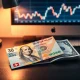 Swiss Franc and US Dollar banknotes on a desk with a financial chart in the background.
