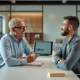 Financial advisor and client discussing investments in a modern office, with an AI interface visible on a laptop in the background