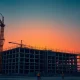 Construction cranes and steel framework at a large industrial infrastructure site at dusk