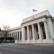 Federal Reserve building in Washington, D.C., with classical marble columns under a cloudy sky