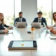 Team in a meeting with a phone showing a calendar notification, representing Calendly's AI note-taker