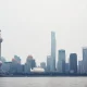 Shanghai skyline with Oriental Pearl Tower under overcast sky, reflecting subdued economic conditions