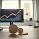 Danish krone and euro coins on a desk with an EUR/DKK chart on a monitor