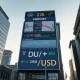 Financial market display showing DXY and gold price charts in a city setting