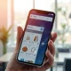 Hand holding smartphone with e-commerce storefront and AI data streams visualizing real-time shopper intent prediction