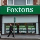Foxtons estate agency storefront in London on a cloudy day, with property listings visible in the window.