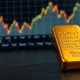 Gold bullion bar with blurred financial chart in background