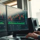 Trading desk with monitors showing stock charts and options data for PZZA, CRK, and KRYS.