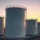 Natural gas storage facility at dusk with large white tanks under a warm sky
