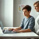 Teenager using ChatGPT on a laptop with a parent nearby in a home study setting