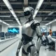 Engineers work alongside a humanoid robot in a modern robotics lab, monitoring data on screens.